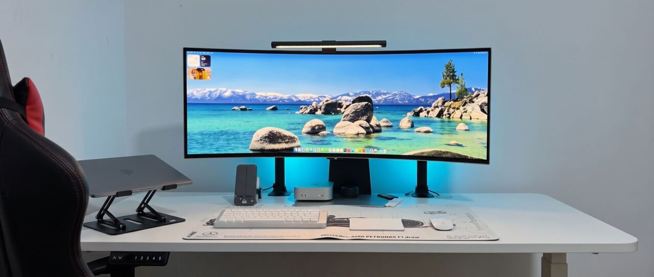 White standing desk with curved ultrawide monitor and light bar